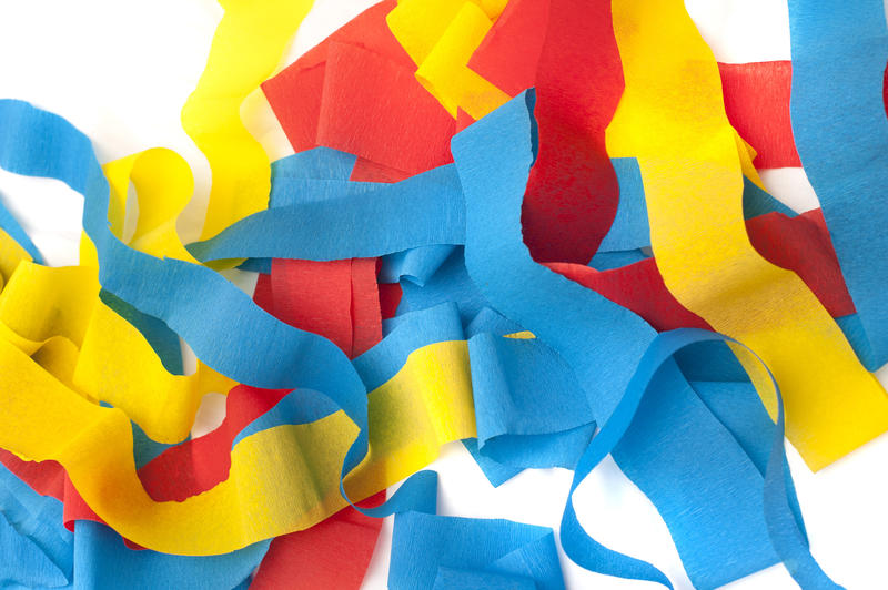 Pile of colorful paper party streamers in red, yellow and blue ready to decorate a festive venue for a celebration, full frame background