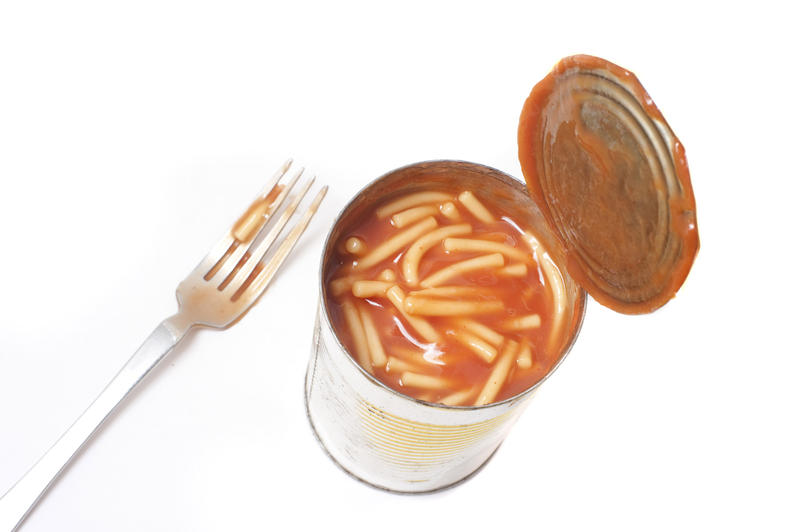 High angle view of a full open can of spaghetti in tomato sauce on a white background for a fast convenient cheap snack