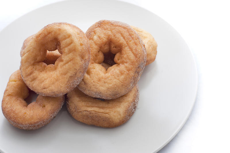 Four freshly baked sugared ring doughnuts served on a plate for breakfast or a coffee break
