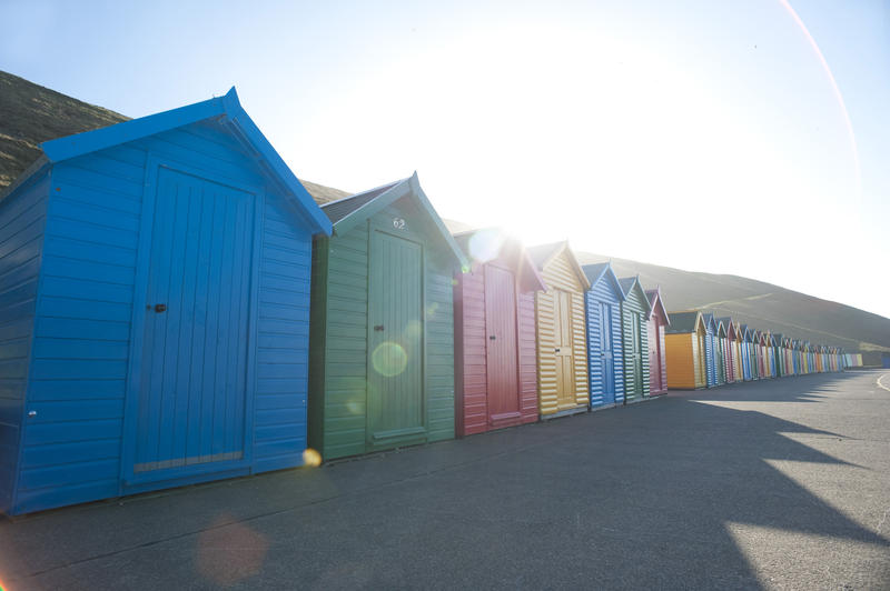 Brightly coloured beach huts over the sunlight in Whitby West Cliff
