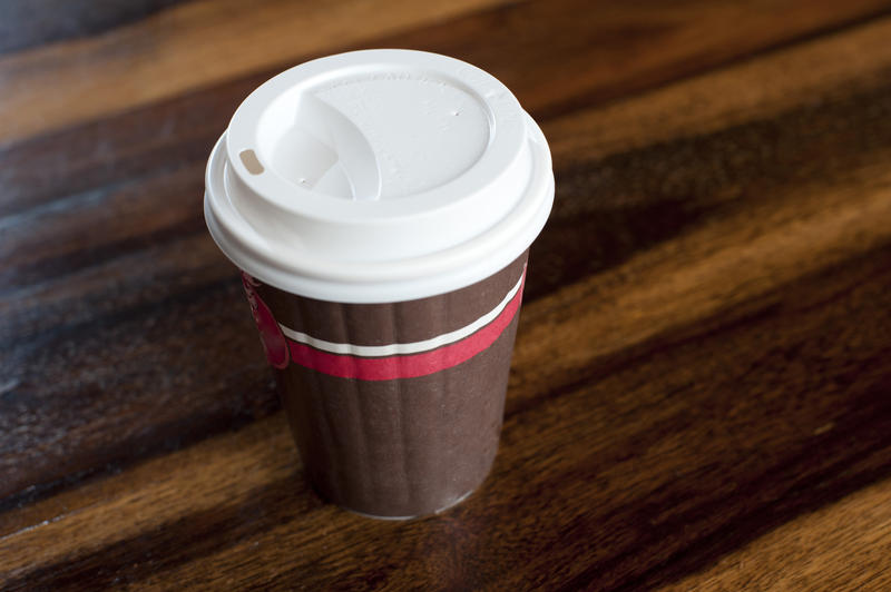 Close up Brown Disposable Coffee Cup with White Cover on a Wooden Table for Takeaway.