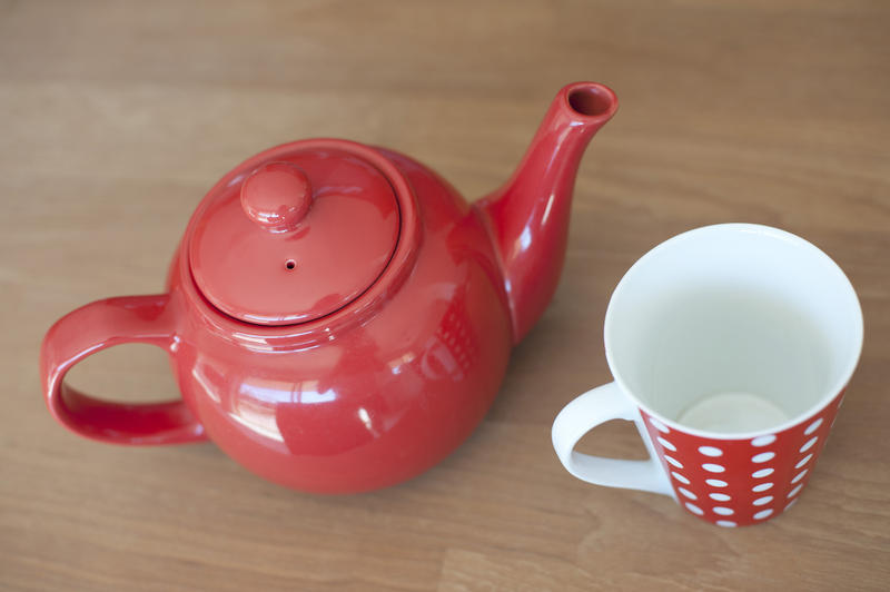 Close up Glossy Red Teapot and an empty cup for One Cup on Top of a Wooden Table