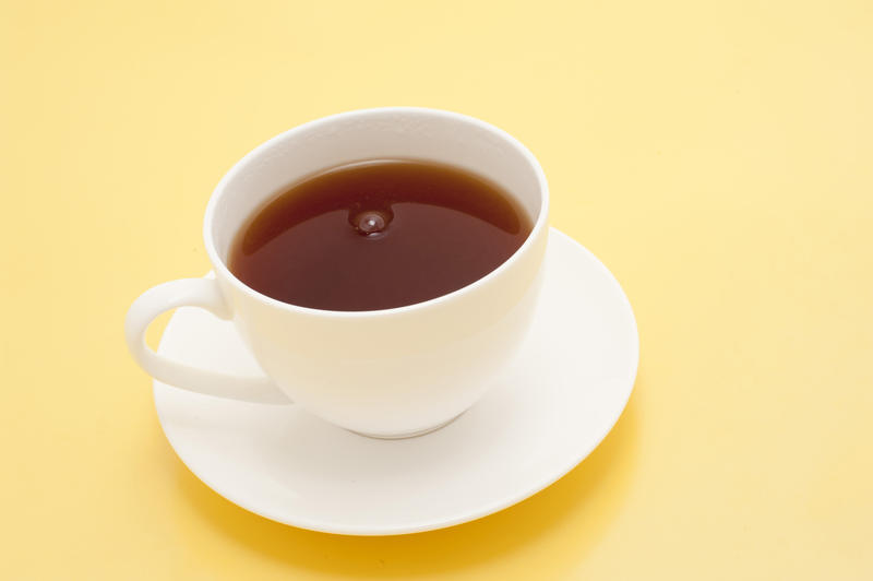 High angle view of a freshly brewed cup of refreshing hot black tea on a yellow background with copyspace