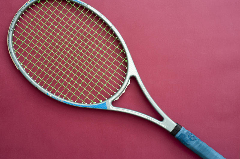 Close up One Racket for Tennis Sports, Isolated on Dark Pink Background