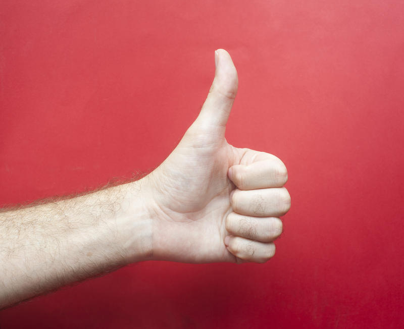 Close up Conceptual Human Hand Showing Thumbs-up on Red Gradient Background