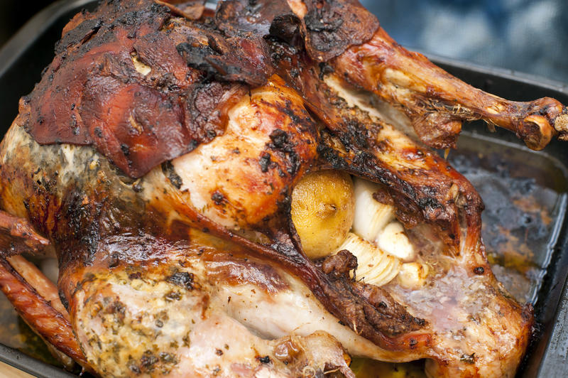 Whole roast turkey in a roasting tray with marinade and dripping during the cooking and preparation of a festive holiday meal for Thanksgiving or Christmas