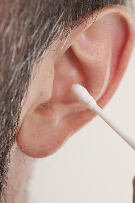 Extreme Macro Close Up of Man Cleaning Ear with Cotton Stick Swab Q-Tip in Studio with White Background