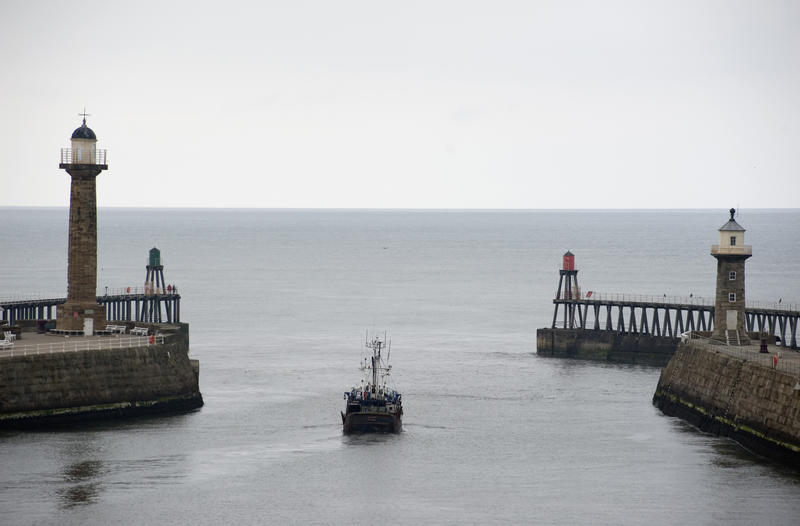 Fishing boat between the two piers of Whitby harbour going out to the open sea