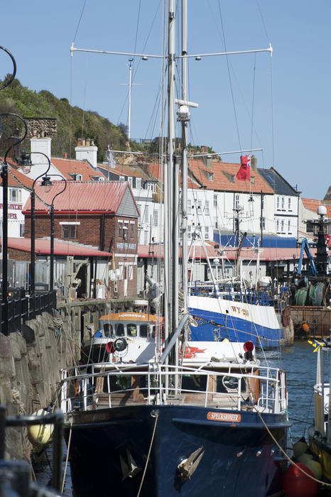Fishing boats and trawlers moored at the wharf and quay in Whitby harbour, a busy fishing town on the Yorkshire coast