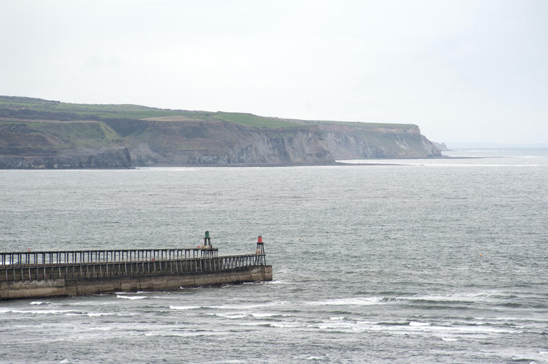 Whitby breakwaterson a misty day with the headlands and coastline visible in the distance across the ocean
