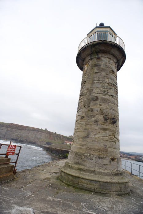 Low angle view of the cylindrical stone lighthouse which acts as a warning and guide to navigation on one of the piers at the entrance to Whitby harbour