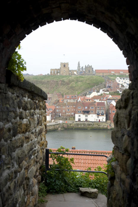View through a stone arch at Saint Mary's church and Abbey ruins in Whitby