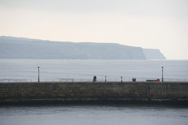 A section of the stone pier at Whitby harbour on a misty day