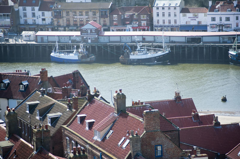 View of fishing boats moored at the wharf in front of the Fish market in Whitby on the Yorkshire coast