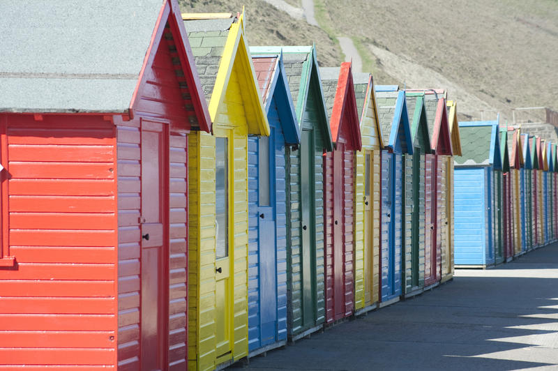 Row of colourful wooden beach huts for changing into swimwear on the beach at Whitby Sands, West Cliff