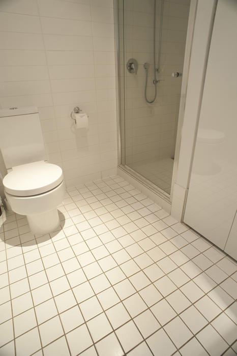 Simple White Tiled Flooring at the Bathroom with Clean Closed Toilet.and Separated Shower Room