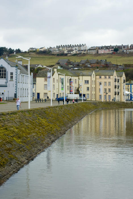 View of buildings along the waterfront at Whitehaven Harbour with people walking along the promenade