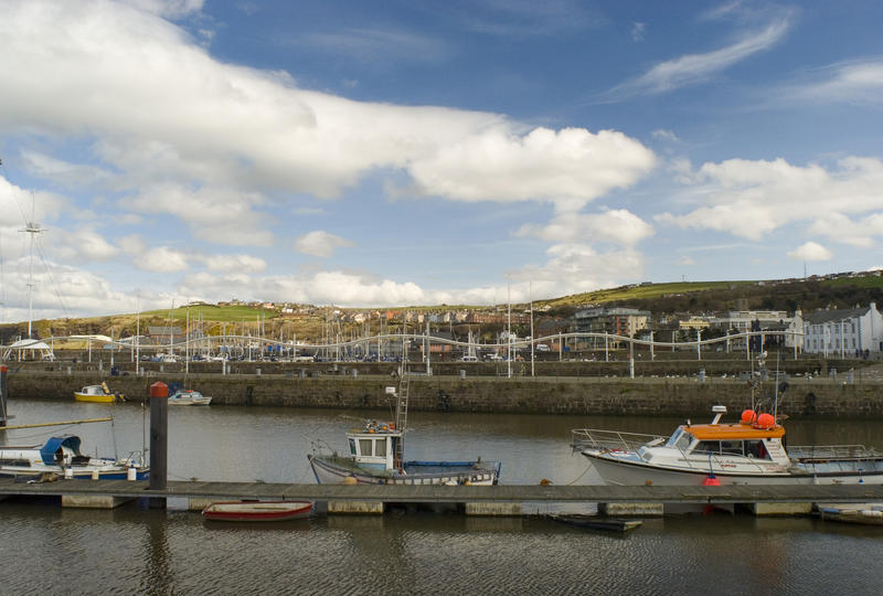 Small fishing craft moored at a wooden jetty in Whitehaven harbour with a view of the waterfront area behind