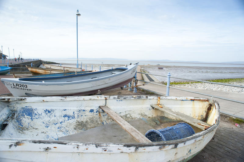 Old small wooden fishing boats beached on the quay above the beach and sands overlooking Morcambe Bay at Morecambe in Lancashire