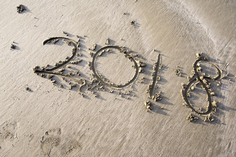 Year 2018 written in the sand on a beach, concept of summer sun