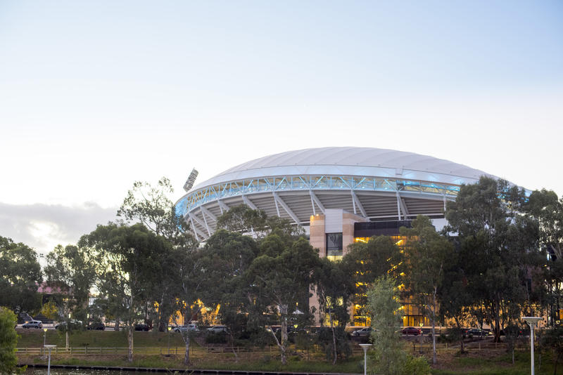 Exterior view of the Adelaide Oval or cricket and sports stadium, South Australia viewed over trees at dusk