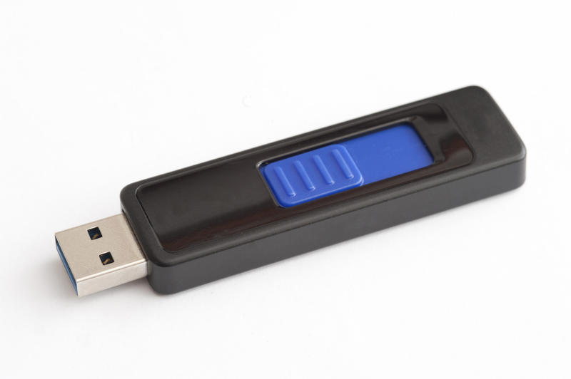Single isolated plastic and metal USB thumb flash drive with blue switch over white background