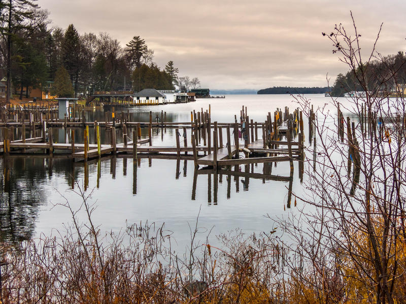 <p>The piers with overcast skies and pilons and boat docks on a lake in the Champlain Valley, rural Vermont.</p>
