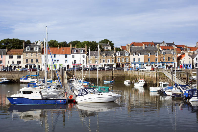 Pleasure Boats Docked in Harbor Lined with Quaint Homes in Village of Anstruther, Scotland on Sunny Day with Blue Sky