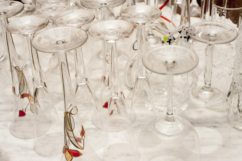 Assorted clean upturned drinks glasses with conical cocktail glasses and wineglasses on a white counter