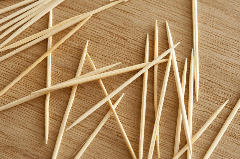 Loose wooden toothpicks or cocktail sticks scattered on a bamboo board in a close up overhead view