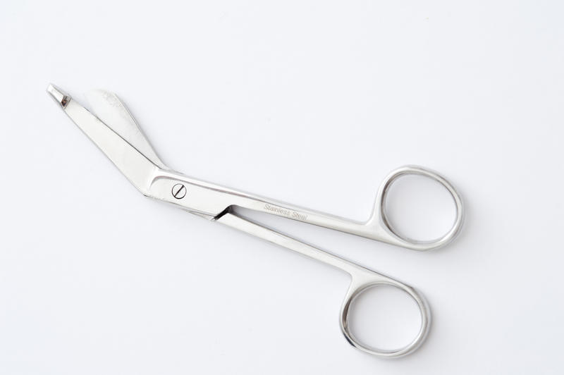 Pair of surgical bandage scissors with angled points to facilitate entering between the skin and fabric when a bandage is in situ on a patient, diagonal view over white