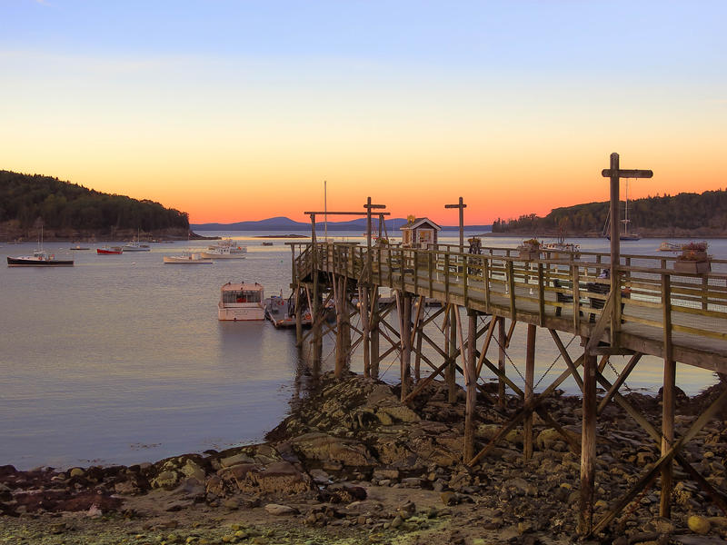 <p>Peir at Bar Harbor Maine at sunset looking West and low tide with rocks and boats.</p>
