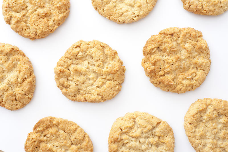 Top down view on cropped white tray with evenly spaced freshly baked round biscuit cookies