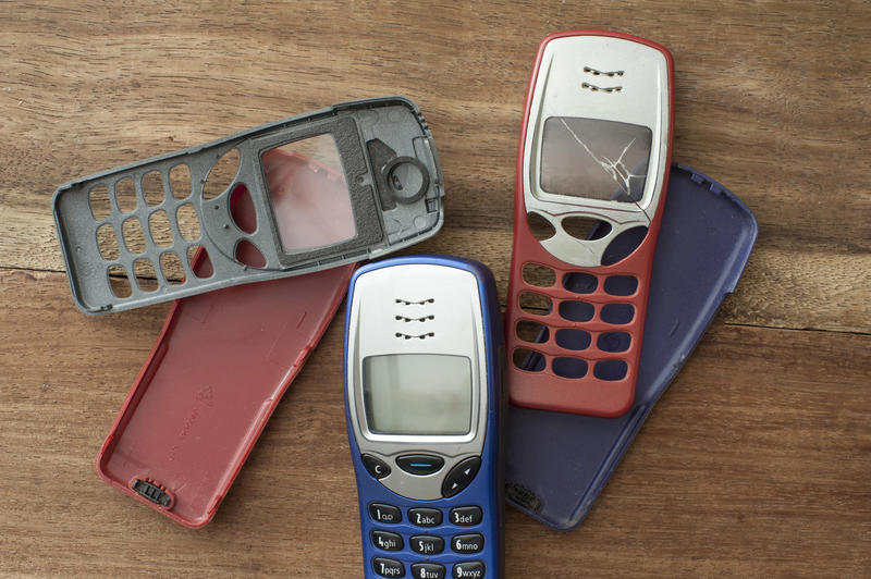 Broken phone cases of old fashioned push-button feature phones close-up on wooden table background