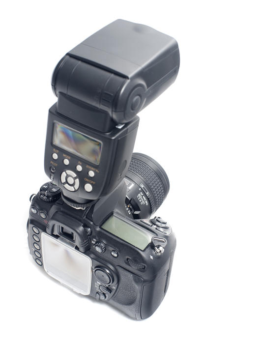 High angle rear view of SLR camera back, LCD display and adjustable flash strobe light over white background