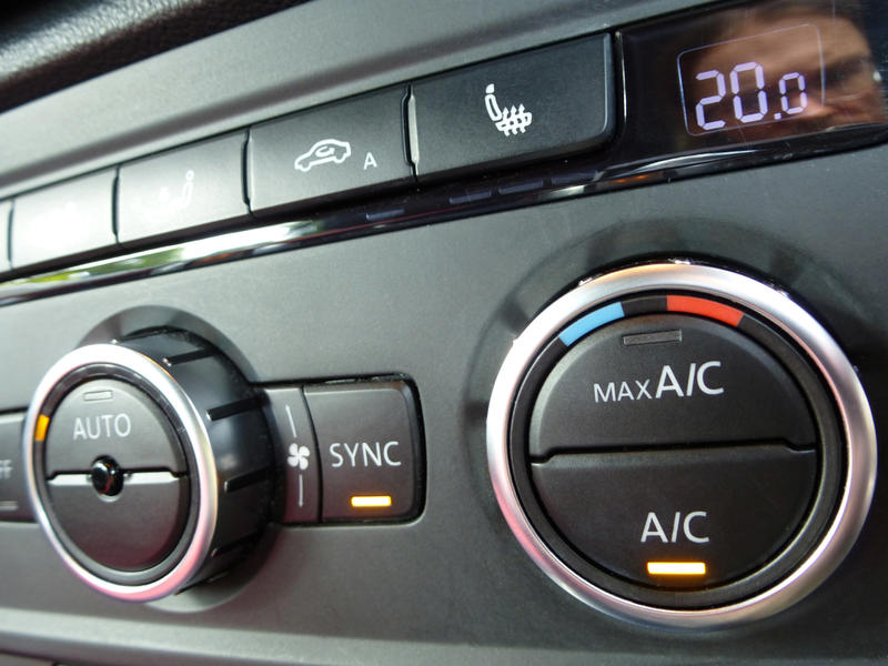 Air conditioner controls on a black car dashboard to control the interior temperature of the vehicle