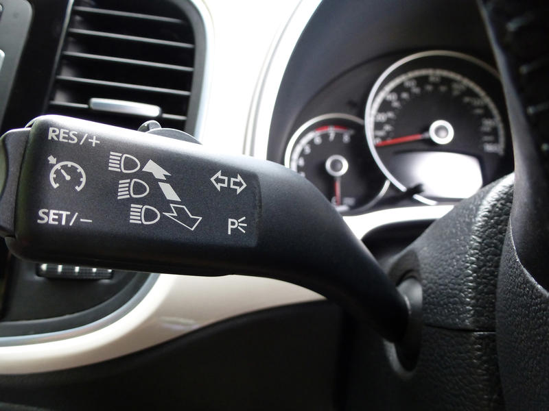 Close up detail of headlight and cruise control lever inside automobile with neutral color scheme