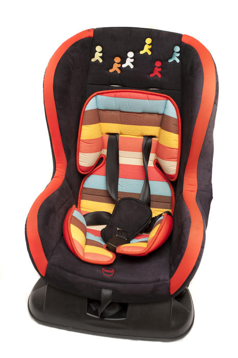 Colorful baby safety car seat for a young child decorated with striped fabric and little running figures isolated on white
