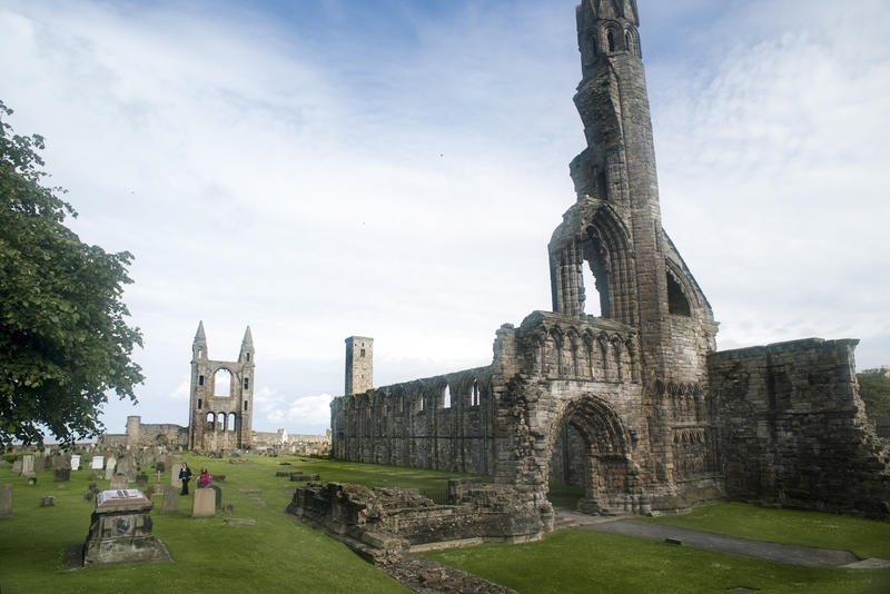 View from the grounds across green lawns of the ancient medieval stone ruins of St Andrews Cathedral, Scotland in a travel concept
