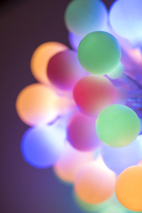 Colorful bundle of glowing round Christmas lights in pastel or muted coors with shallow dof in a festive holiday background