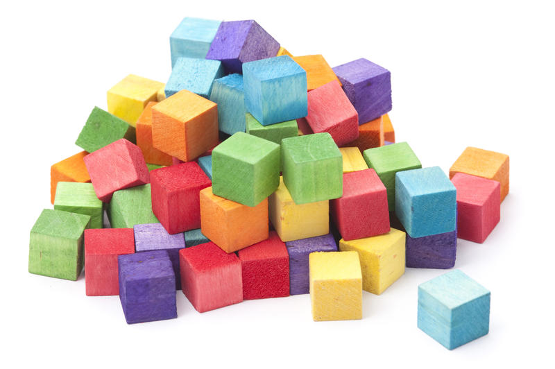 Heap of colorful wooden educational kids building blocks or cubes in the colors of the rainbow over a white background
