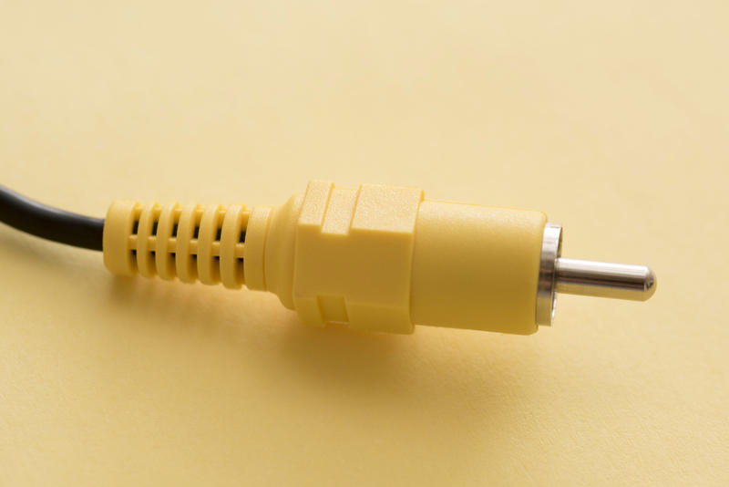 Yellow composite RCA video connection plug close-up on plain yellow background