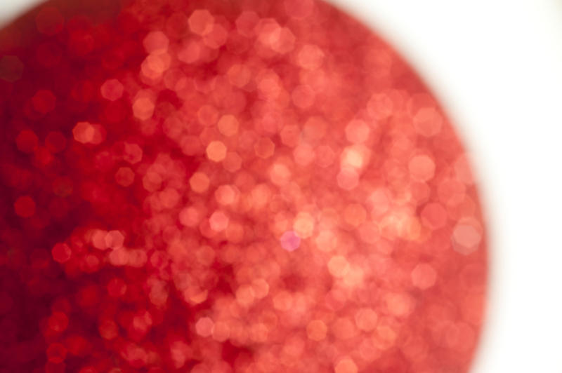 Close Up of Diffuse Red Glitter Ball - Festive Still Life of Abstract Ball Covered with Red Sequins on White Background with Copy Space