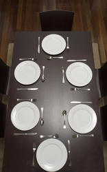 17151   Dark wood dining table laid with clean plates