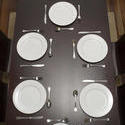 17151   Dark wood dining table laid with clean plates