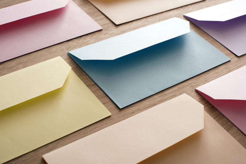 Rows of colorful paper blank Easter cards envelopes over wooden table, invitation concept background