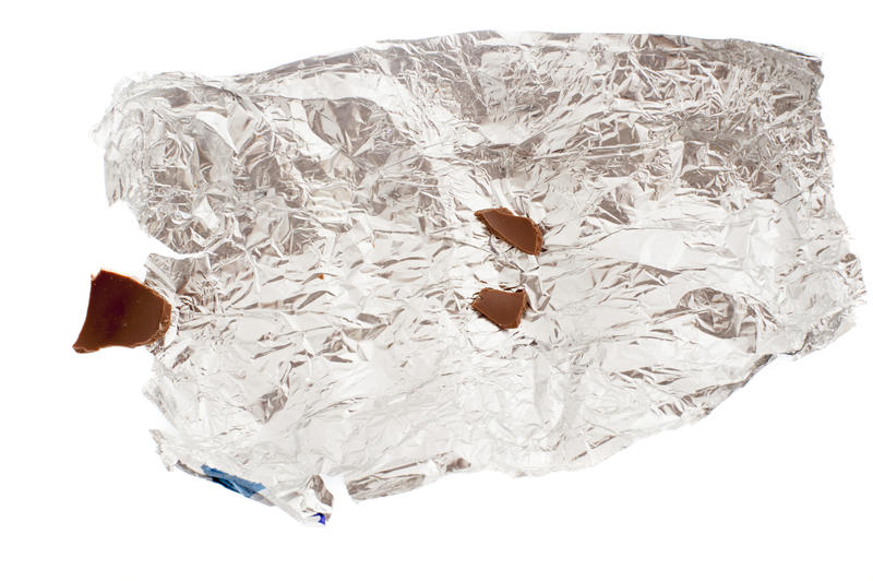 Close up view of crumpled foil with remains of chocolate pieces of eaten Easter Bunny candy isolated on white background