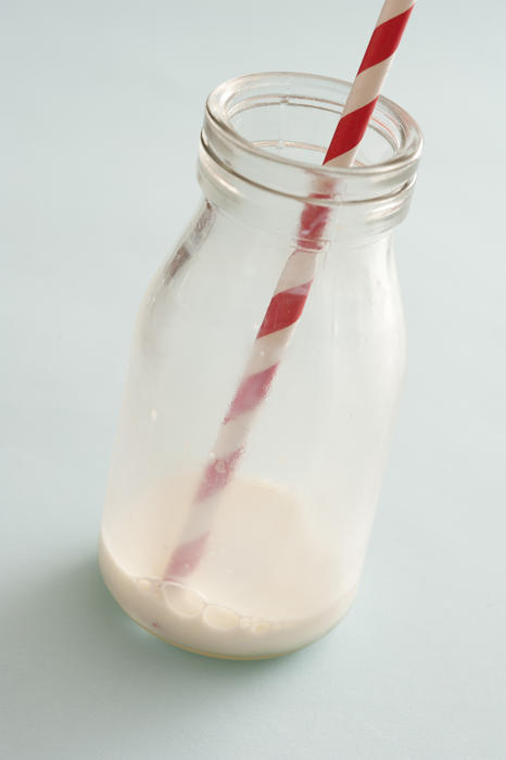 Remnants of milk in a glass bottle with straw after the contents have been drunk or consumed in a healthy diet concept