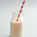 13003   Small glass bottle full of milk with a straw