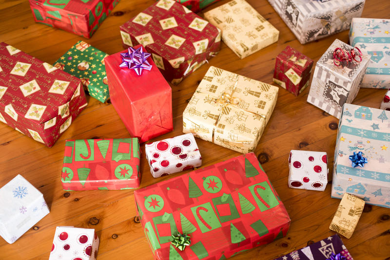 A close up of various, unopened Christmas presents on timber floor.